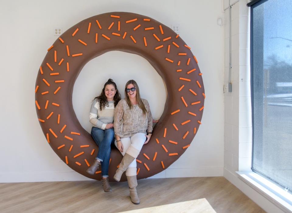 Jenni Pinson, left, and Patti Yost pose in the giant selfie doughnut at the newest location of Tadoughs doughnut shop in the Tanglewood Shopping Center in Peoria.