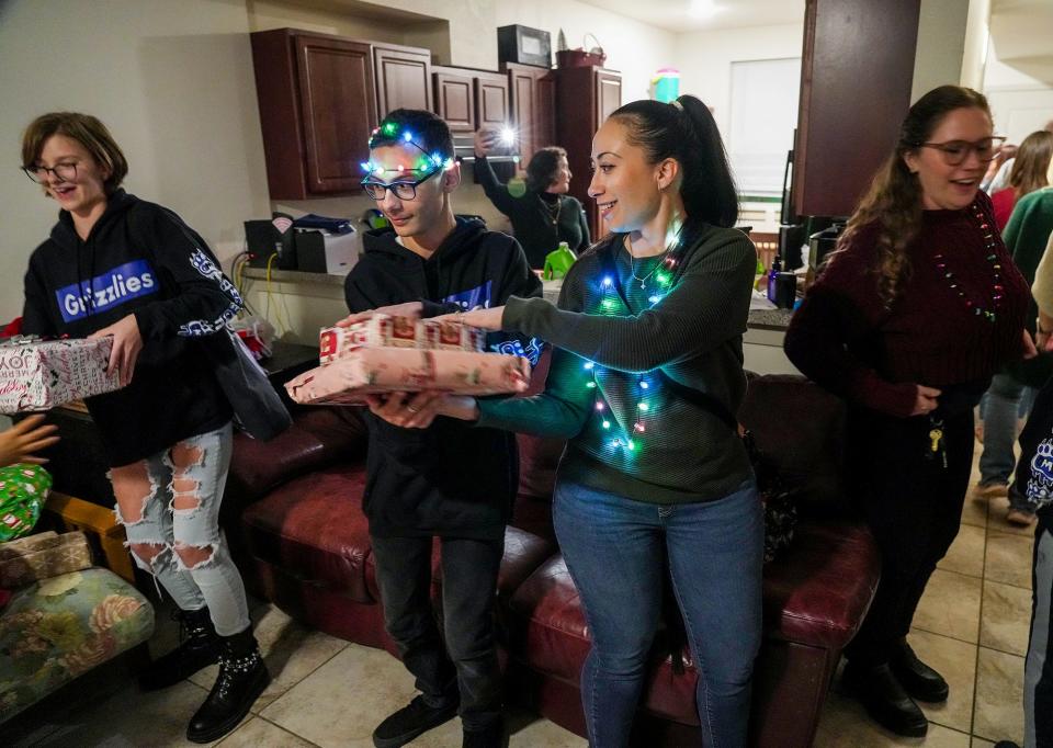 From left, Riley Pukall, Ali Arghami and his mom, Krista Arghami, form a line with other students from Grisham Middle School as they present gifts to the Ramirez family.