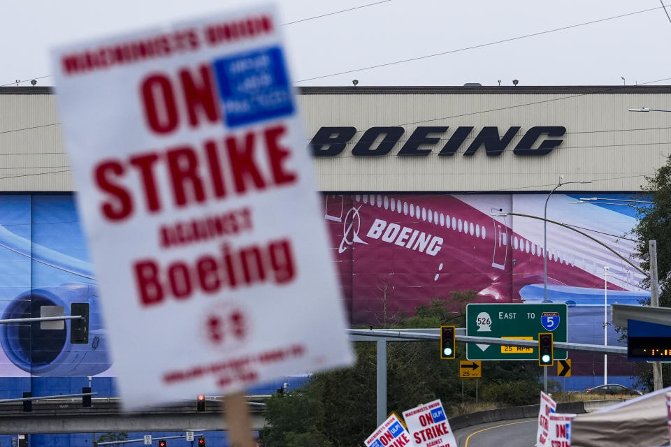 Pekerja Boeing Co. melambaikan tanda piket saat mereka mogok setelah anggota serikat pekerja memilih untuk menolak tawaran kontrak, Minggu, 15 September 2024, di dekat pabrik perusahaan di Everett, Washington. (Foto AP/Lindsey Wasson)