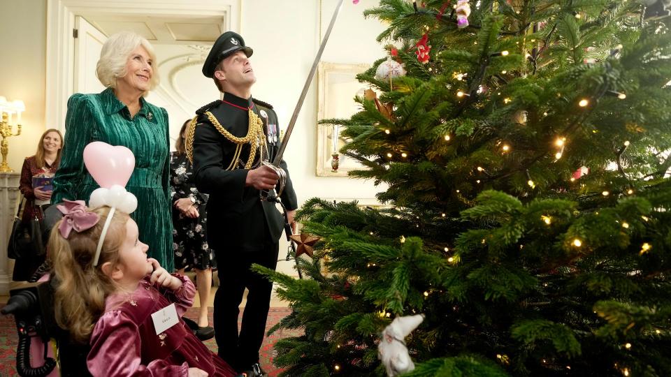 Major Oliver Plunket places decoration on Clarence House xmas tree with sword