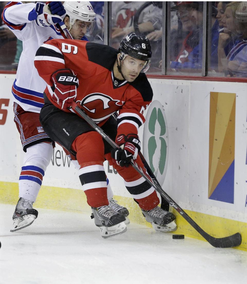 New Jersey Devils' Andy Greene (6) keeps the puck away from New York Rangers' Mats Zuccarello, of Norway, during the first period of an NHL hockey game game Saturday, March 22, 2014, in Newark, N.J. (AP Photo/Mel Evans)