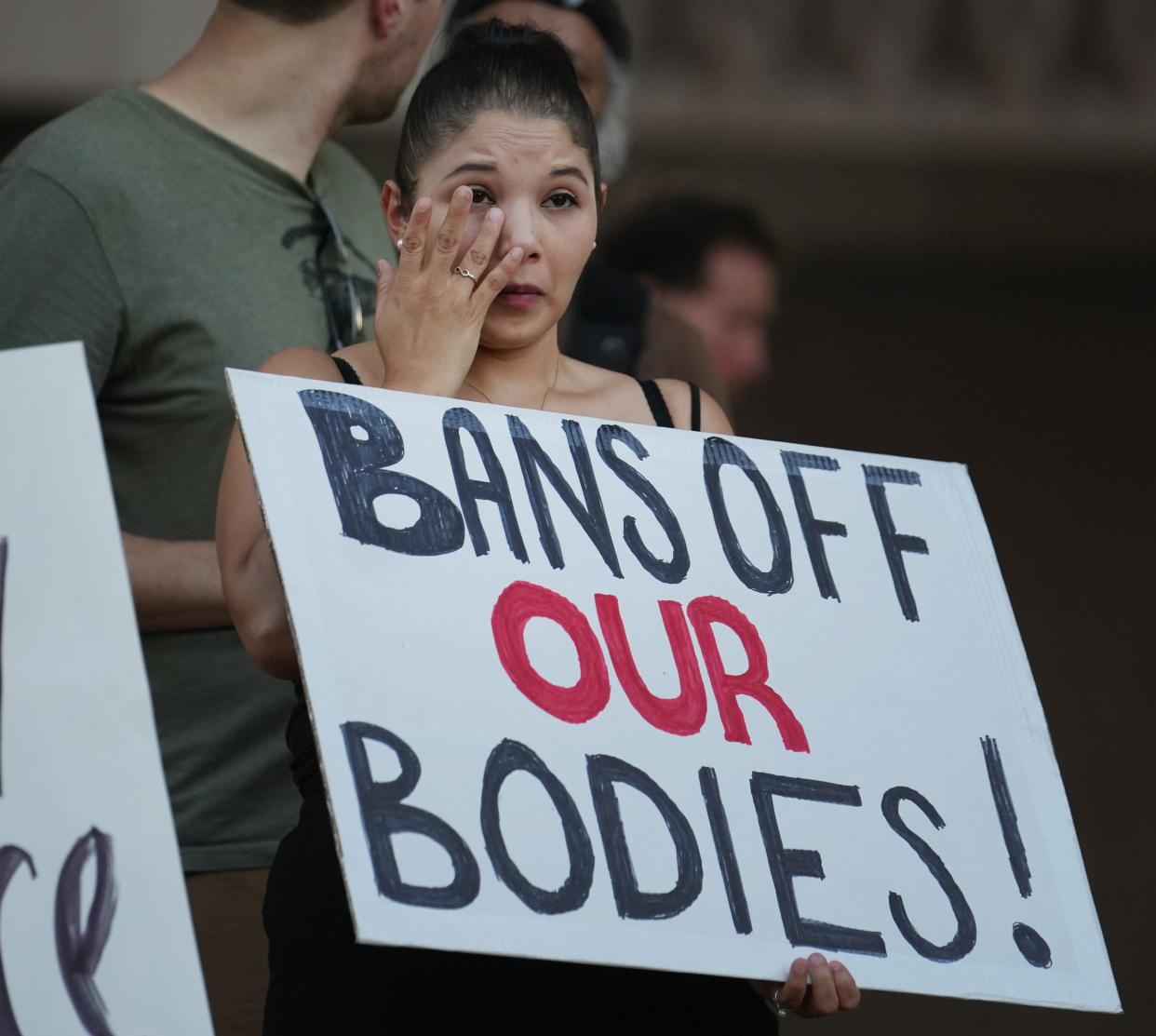 Jasmine Held-Hernandez wipes away a tear as she listens to stories from fellow abortion rights demonstrators gathered at the Arizona Capitol in Phoenix on Sept. 24, 2022.