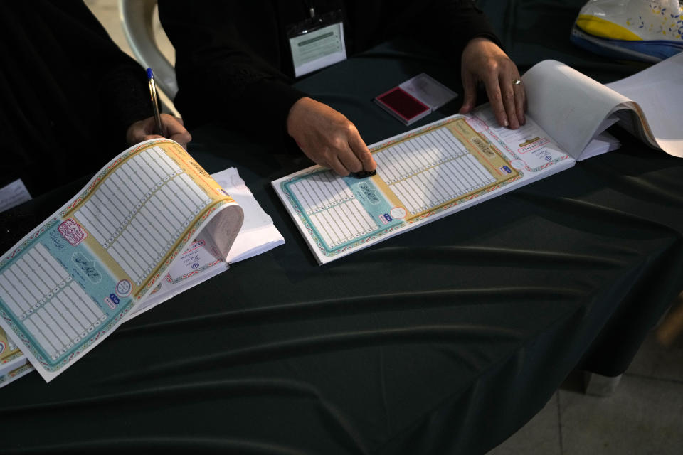 A staff member of a polling station prepares ballot papers for voters during the parliamentary and Assembly of Experts elections at a polling station in Tehran, Iran, Friday, March 1, 2024. Iran began voting Friday in its first elections since the mass 2022 protests over its mandatory hijab laws after the death of Mahsa Amini, with questions looming over just how many people will turn out for the poll. (AP Photo/Vahid Salemi)