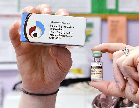 A nurse holds up a vial and box for the HPV vaccine, brand name Gardasil.