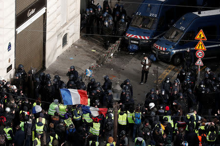 Protesters wearing yellow vests and waving French flags face off with French Gendarmes during clashes on the Champs-Elysees Avenue as part of a demonstration by the "yellow vests" movement in Paris, France, December 8, 2018. REUTERS/Benoit Tessier