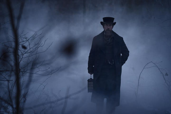 Christian Bale holds a lantern in The Pale Blue Eye.