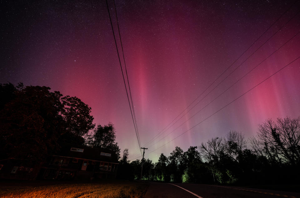 Starry night sky, tinted red, seen through power lines.