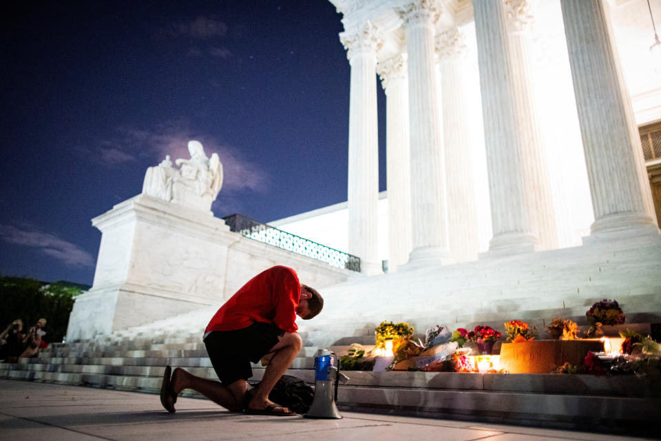 A man kneels outside the Supreme Court before tributes to the Justice Ruth Bader Ginsburg following her death on Friday. (Photo: Alexander Drago /Reuters)