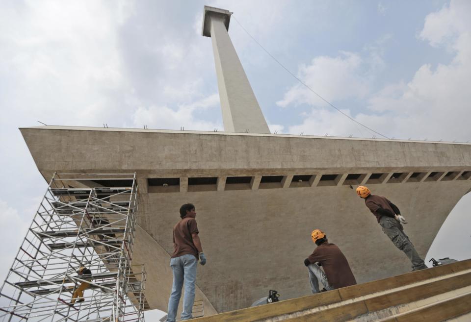 In this Thursday, May 8, 2014 photo, workers stand at the base of the National Monument to prepare for its cleaning in Jakarta, Indonesia. The 132-meter (433-feet) tall monument, a popular landmark in the capital, is being cleaned for the first time in more than two decades. German-based Kaercher company, which specializes in the cleaning of cultural monuments, is doing the work. It also did the monument’s last cleaning in 1992. (AP Photo/Dita Alangkara)