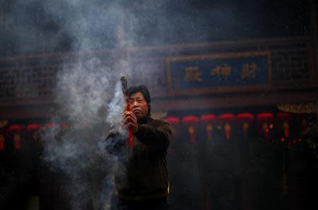 A man burns incense at the Old City God Temple in Yuyuan Garden, downtown Shanghai in this January 18, 2011 file photo. REUTERS/Carlos Barria/Files
