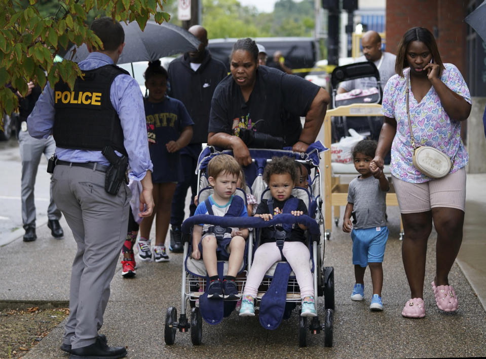 Children escorted out of the Community Preschool & Nursery on Penn Ave. during a standoff in the Garfield neighborhood of Pittsburgh, Wednesday, Aug. 23, 2023. A person facing eviction opened fire from inside a Pittsburgh home Wednesday and was later pronounced dead after a siege that lasted much of the day, authorities said. (Sebastian Foltz/Pittsburgh Post-Gazette via AP)