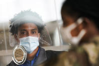 FILE - In this Oct. 20, 2020, file photo, transportation Security Administration personnel and travelers observe COVID-19 transmission prevention protocols at John F. Kennedy International Airport in the Queens borough of New York. The United States is approaching a record for the number of new daily coronavirus cases in the latest ominous sign about the disease's grip on the nation. (AP Photo/John Minchillo, File)