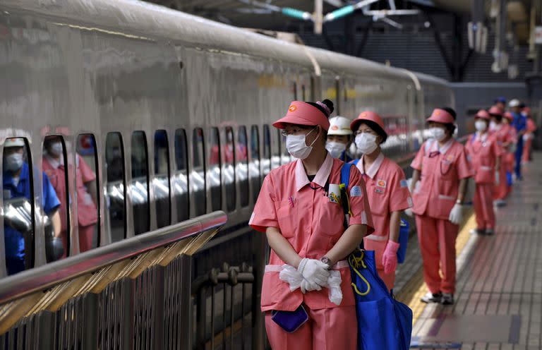 Empleadas del servicio de limpieza, con mascarillas, en una estación de trenes de Tokio