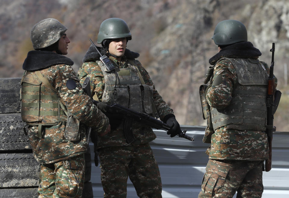 Ethnic Armenian militants stand at a checkpoint near village of Charektar in the separatist region of Nagorno-Karabakh at a new border with Kalbajar district turned over to Azerbaijan, Wednesday, Nov. 25, 2020. The Azerbaijani army has entered the Kalbajar region, one more territory ceded by Armenian forces in a truce that ended deadly fighting over the separatist territory of Nagorno-Karabakh, Azerbaijan's Defense Ministry said Wednesday. The cease-fire, brokered by Russia two weeks ago, stipulated that Armenia hand over control to Azerbaijan of some areas its holds outside Nagorno-Karabakh's borders. (AP Photo/Sergei Grits)