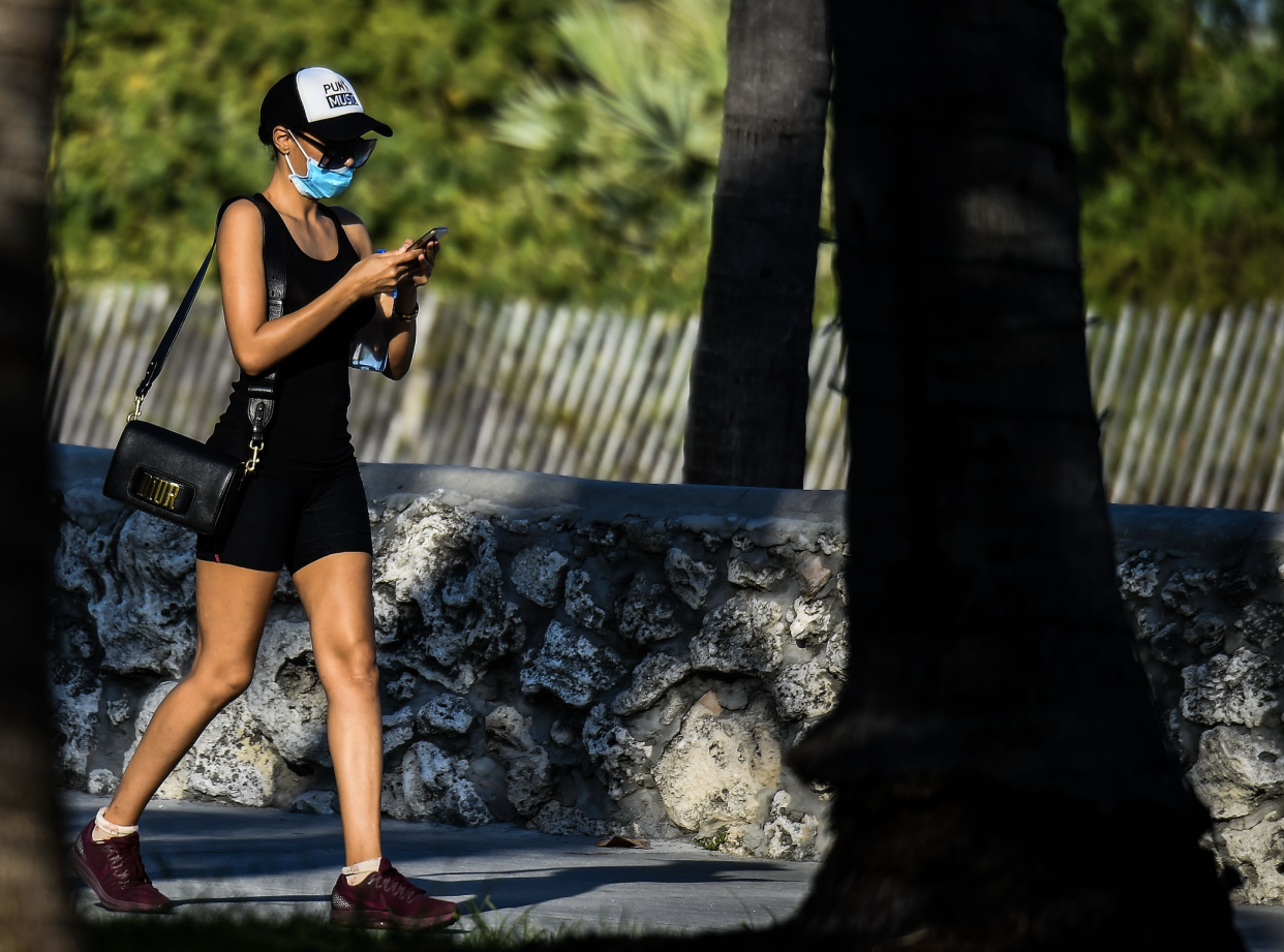 A woman wears a mask as she walks on Ocean Drive in South Beach, Miami, amid fears over the spread of the novel coronavirus (COVID-19) on March 31, 2020. (Photo: CHANDAN KHANNA / AFP) (Photo by CHANDAN KHANNA/AFP via Getty Images) 