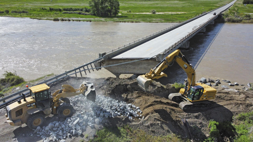 Highway workers build up the shoreline of a washed out bridge along the Yellowstone River Wednesday, June 15, 2022, near Gardiner, Mont. Yellowstone National Park officials say more than 10,000 visitors have been ordered out of the nation's oldest national park after unprecedented flooding tore through its northern half, washing out bridges and roads and sweeping an employee bunkhouse miles downstream. (AP Photo/Rick Bowmer)