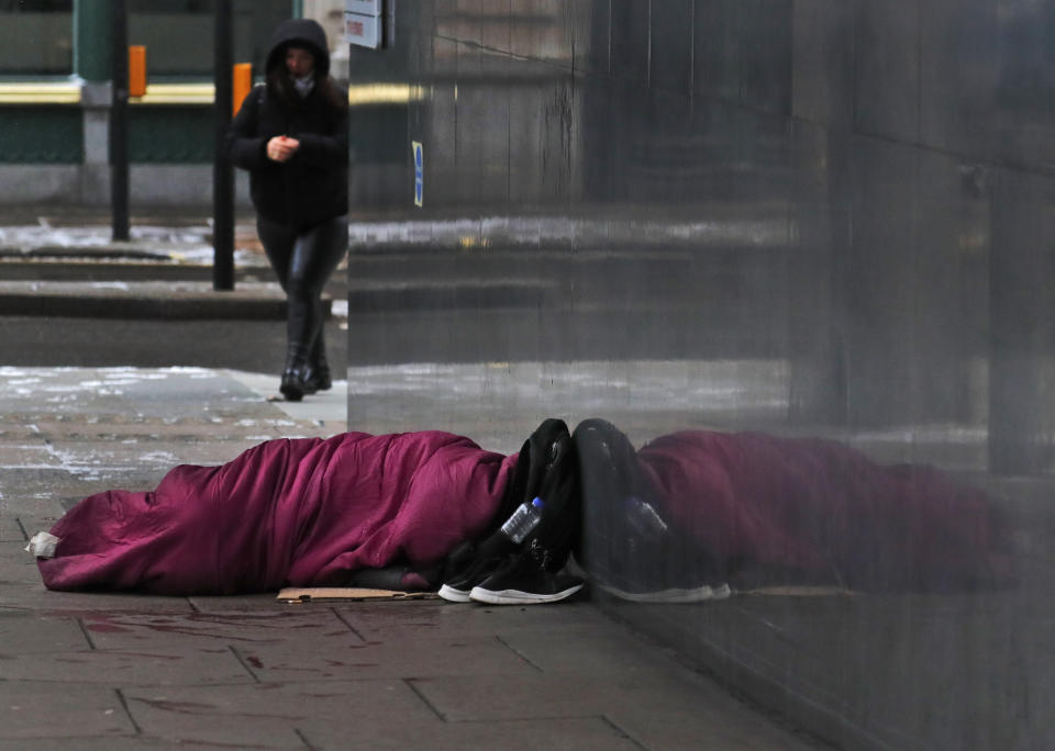 A rough sleeper seeks shelter close to a wall in London, Monday, Feb. 8, 2021. In the battle against COVID-19, the homeless are not listed among the British government's highest priority groups for the vaccine rollout — currently people over 70 years old, care home residents, frontline health and social care workers, as well as the clinically vulnerable. (AP Photo/Frank Augstein)