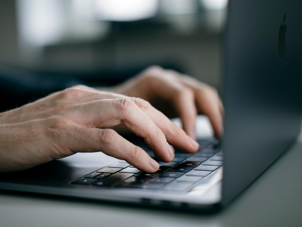 Hands typing on a Macbook keyboard