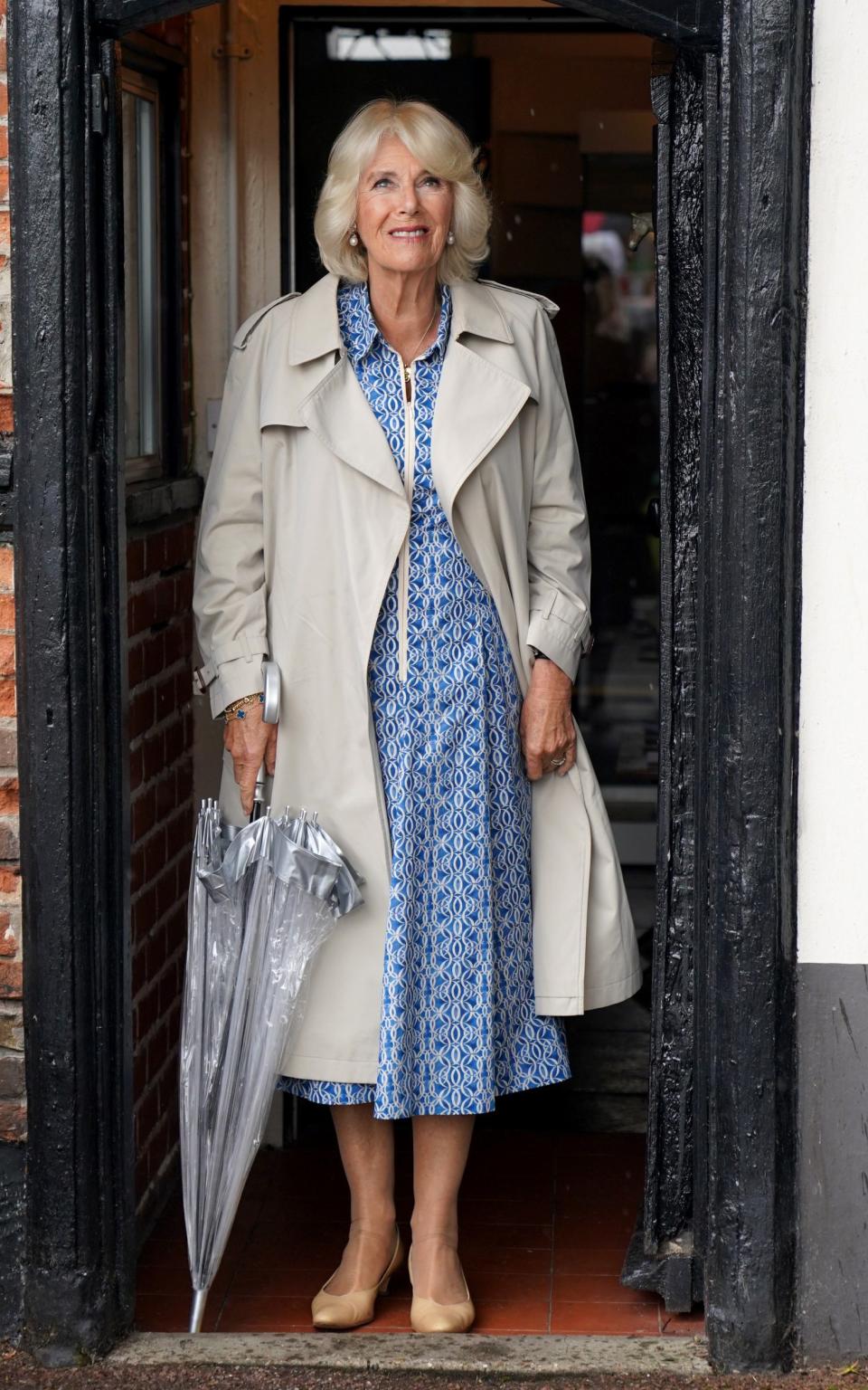 Queen Camilla looks out of a doorway at the rain during a visit to Redwings Horse Sanctuary at Anna Sewell House on July 24, 2023