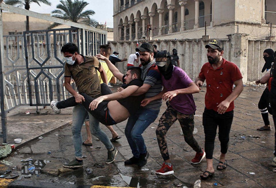 An injured protestor is rushed to a hospital during a demonstration in central Baghdad, Iraq, Friday, Oct. 25, 2019. Iraqi police fired live shots into the air as well as rubber bullets and dozens of tear gas canisters on Friday to disperse thousands of protesters on the streets of Baghdad, sending young demonstrators running for cover and enveloping a main bridge in the capital with thick white smoke. (AP Photo/Khalid Mohammed)