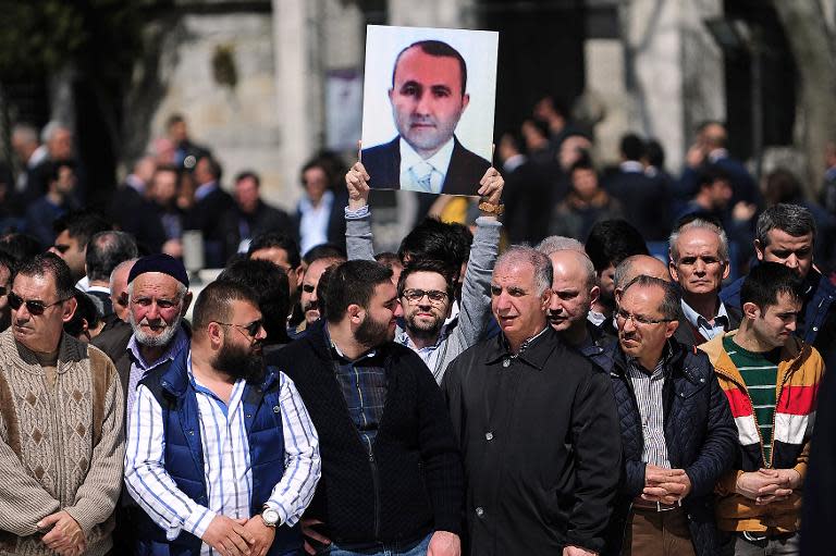 A man holds a portrait of prosecutor Mehmet Selim Kiraz during a funeral ceremony outside the Eyup Sultan Mosque in Istanbul on April 1, 2015