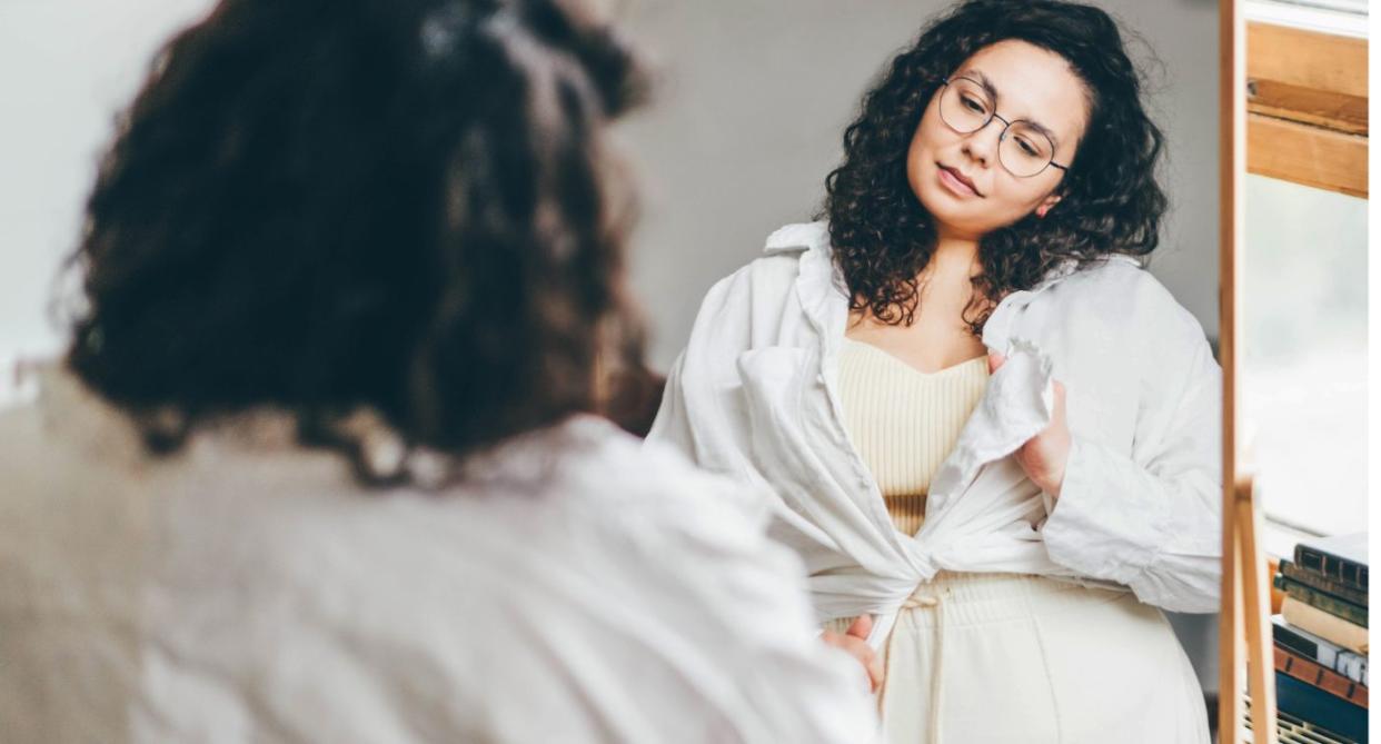 Woman looking in mirror, representing low body confidence. (Getty Images)