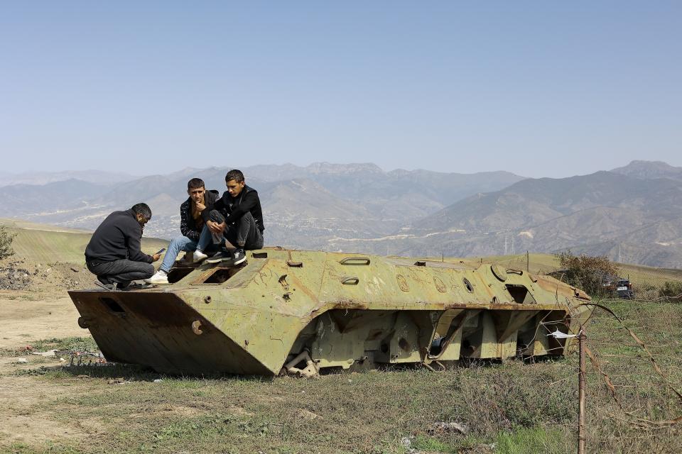 Ethnic Armenian men from Nagorno-Karabakh sit atop of a damaged armored personnel carrier after arriving to Armenia's Kornidzor in Syunik region, Armenia, Friday, Sept. 29, 2023. Armenian officials say more than 70% of Nagorno-Karabakh's original population have fled the region for Armenia. (AP Photo/Vasily Krestyaninov)