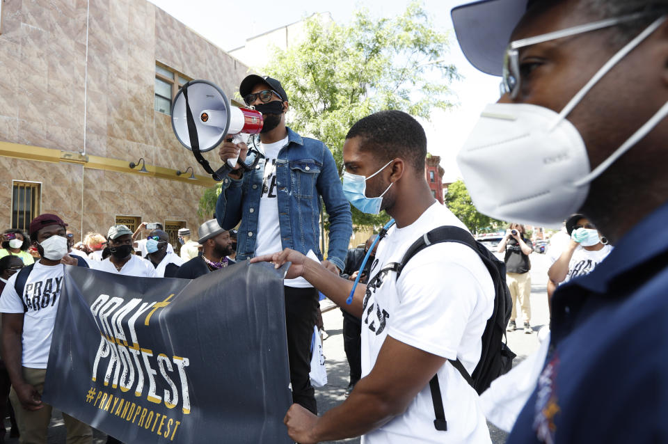 Rev. Brandon Watts, the pastor of Brooklyn's Epiphany Church in Brooklyn, stands in Resurrection Square at the start of a Pray & Protest march, Sunday, June 7, 2020, in the Beford Stuyvesant neighborhood of New York. (AP Photo/Kathy Willens)