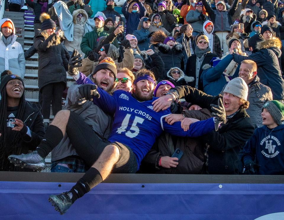 Holy Cross defensive back Hunter Burns leaps into the crowd to celebrate with fans after the Crusaders topped Sacred Heart on Saturday.