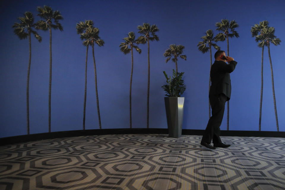 FILE - In this May 4, 2018, file photo a man talks on the phone in a hallway adorned with the palm tree-printed wallpaper at a hotel near the Los Angeles International Airport in Los Angeles. New tools are coming to help fight robocall scams, but don’t expect unwanted calls to disappear. (AP Photo/Jae C. Hong, File)