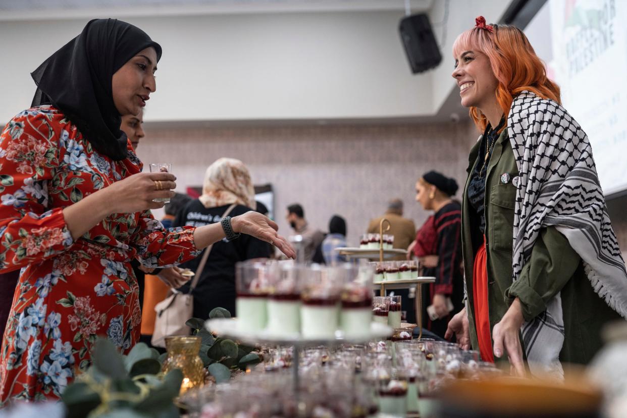 Reema Hammoud, left, of Dearborn talks with chef Lena Sareini while sampling her fig leaf muhallabia with raspberries and pistachios during the Chefs for Palestine event.