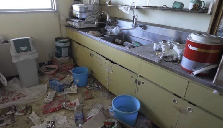 A mess of supplies and buckets left all over the floor in an abandoned Fukushima hospital.