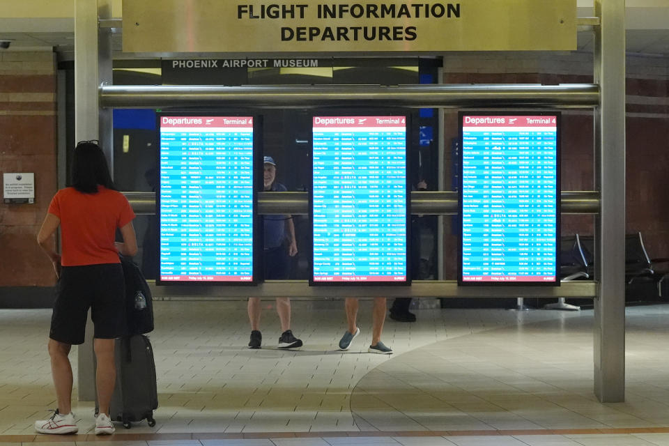 Passengers check departure screens at Phoenix Sky Harbor International Airport Friday, July 19, 2024, in Phoenix. An overnight outage was blamed on a software update that cybersecurity firm CrowdStrike sent to Microsoft computers of its corporate customers including many airlines. (AP Photo/Ross D. Franklin)