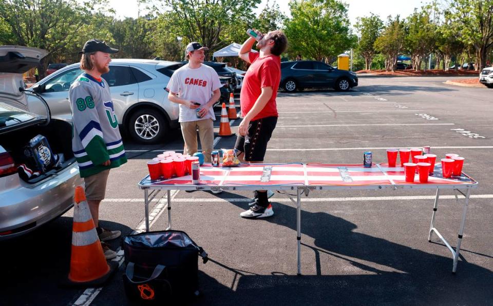 From left Niklas Ehlin of Charlotte, Austin Carroll of Raleigh and Kevin Oakes of Charlotte play pong with water as Carolina Hurricanes fans tailgate before the Canes’ playoff game against the N.Y. Rangers at PNC Arena in Raleigh, N.C. Friday, May 20, 2022.