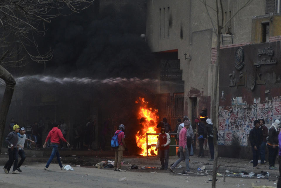 Supporters of Egypt’s ousted President Mohammed Morsi damage a police building as water canon from the building is used to extinguish flames in Cairo's Ain Shams district, Egypt, Friday, Feb. 7, 2014. Clashes between Egyptian security forces and Islamist protesters left one person dead in a province southwest of Cairo on Friday while two home-made bombs targeting policemen wounded six people in a bridge in the capital, officials said. (AP Photo/Mostafa Darwish)