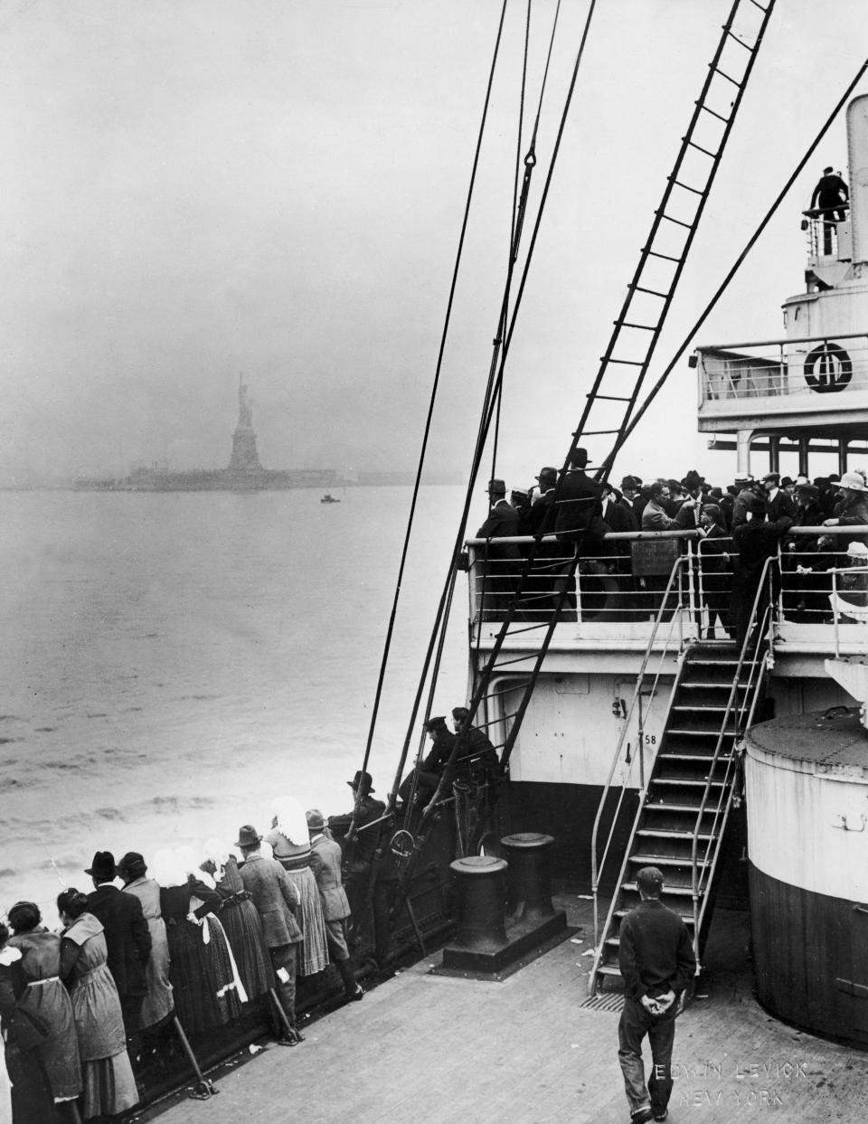 Immigrants view the Statue of Liberty while entering New York harbor aboard an ocean liner en route to Ellis Island, New York City, 1910s.