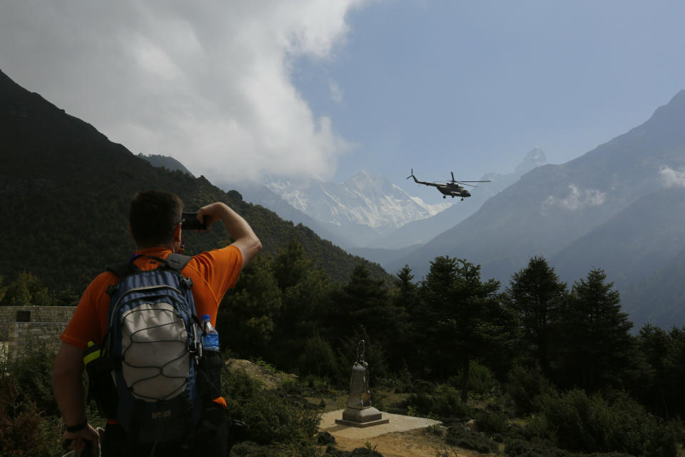 In this May 27, 2019 photo, a tourist takes a photograph of the Mount Everest at Namche Bajar, Solukhumbu district, Nepal. The record number of climbers on Mount Everest this season has left a cleanup crew grappling with how to clear away everything from abandoned tents to human waste that threatens drinking water. (AP Photo/Niranjan Shrestha)