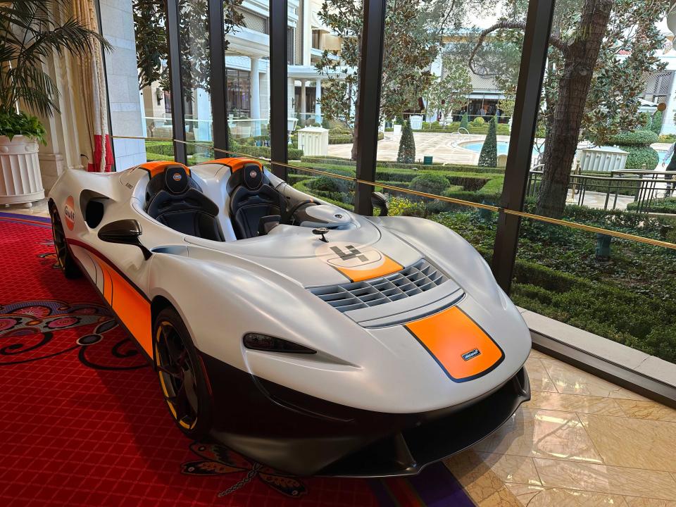 A McLaren sports car parked on a red carpet on display next to a window.