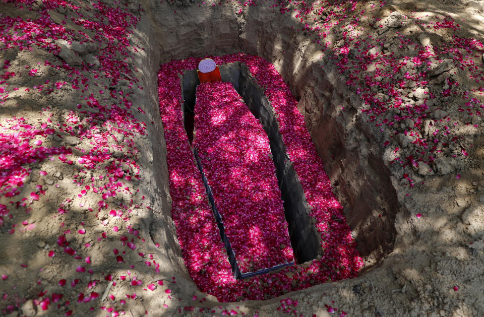 Rose petals are spread around the grave and coffin of Father Rolfie D'Souza's who died of COVID-19, at a cemetery in Prayagraj, India, Saturday, May 15, 2021. India's Prime Minister Narendra Modi on Friday warned people to take extra precautions as the virus was spreading fast in rural areas. (AP Photo/Rajesh Kumar Singh)