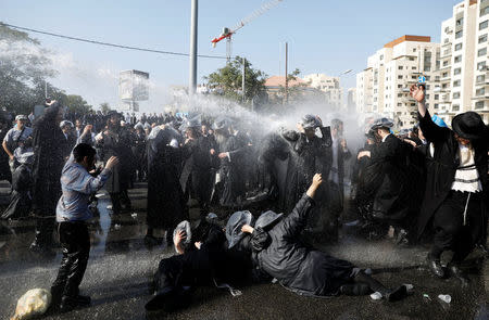 Israeli ultra-Orthodox Jewish men are sprayed with water during clashes with police at a protest against the detention of a member of their community who refuses to serve in the Israeli army, in Jerusalem September 17, 2017. REUTERS/Ronen Zvulun