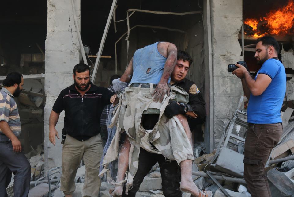 A member of the Syrian Civil Defense, also known as White Helmets, carries a victim following&nbsp;the airstrike at the&nbsp;Maaret al-Numan market. (Photo: MOHAMED AL-BAKOUR via Getty Images)