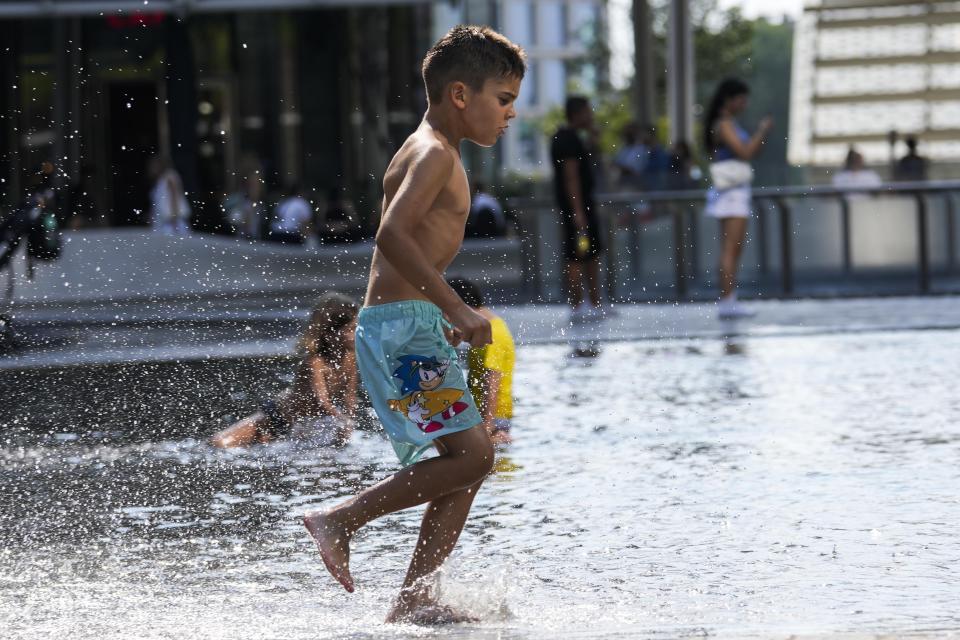 Children cool off in a public fountain in Milan, Italy, Saturday, July 15, 2023. Temperatures reached up to 42 degrees Celsius in some parts of the country, amid a heat wave that continues to grip southern Europe. (AP Photo/Luca Bruno)