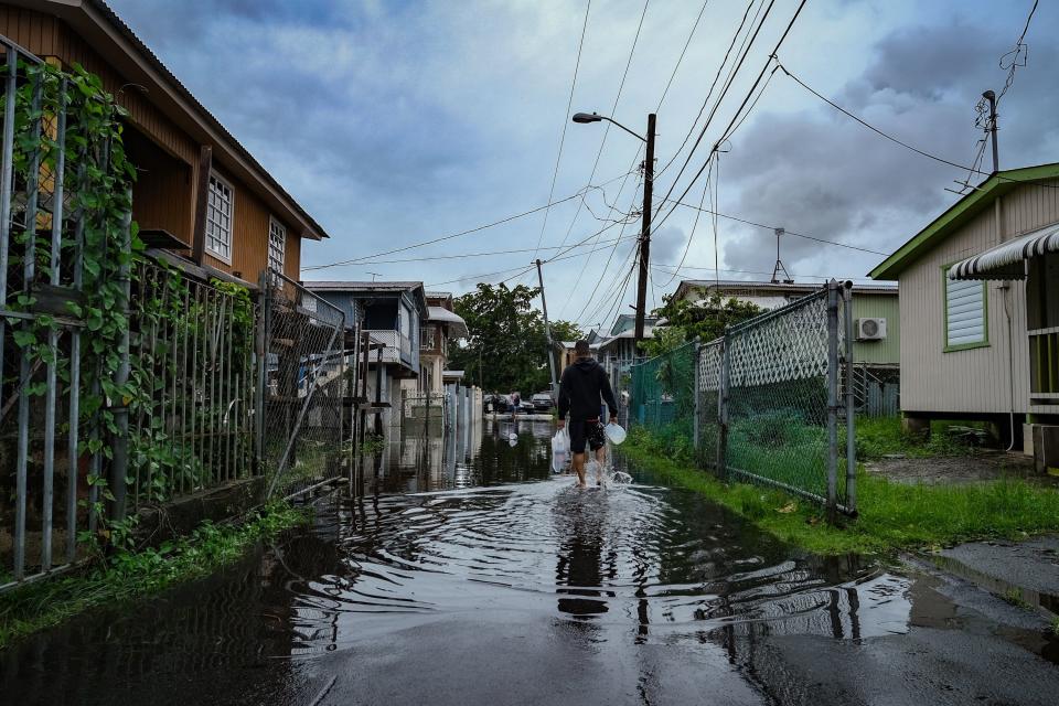A man walks down a flooded street in Catano, Puerto Rico, on Sept. 19, 2022, after the passage of Hurricane Fiona.