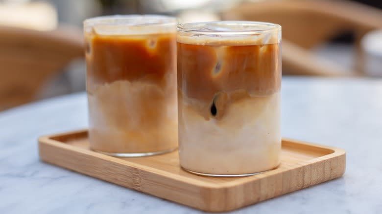 Two glasses of iced coffee on a wooden tray