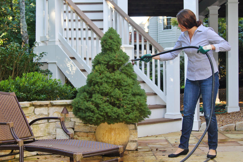 In this 2012 publicity photo provided by PLANET, a woman waters her plants at a private residence in Dunn Loring, Va. Place plants in the right location for sun or shade. Doing so will create less stress on the plants, which will help to keep them disease-free and less stressed under low water conditions. (AP Photo/PLANET, National Landscape Industry Association, Philippe Nobile)