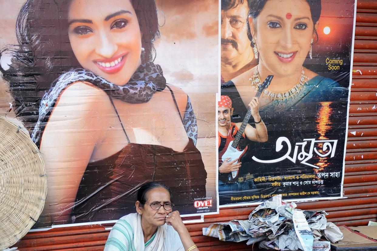 An Indian woman rests in front of Bengali movie posters. Bengali cinema, nicknamed Tollywood, is a portmanteau of the words Tollygunge and Hollywood, which origins dating back to 1932: Dibyangshu Sarkar/AFP/Getty Images