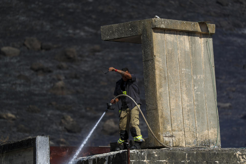 An Israeli firefighter works to extinguish a fire caused by rocket fired from Lebanon into Israeli territory near the northern Israeli town of Kiryat Shmona, Wednesday, Aug. 4, 2021. Three rockets were fired from Lebanon into Israeli territory Wednesday and the army fired back, Israel's military said. There was no immediate information on damages or casualties. (AP Photo/Ariel Schalit)