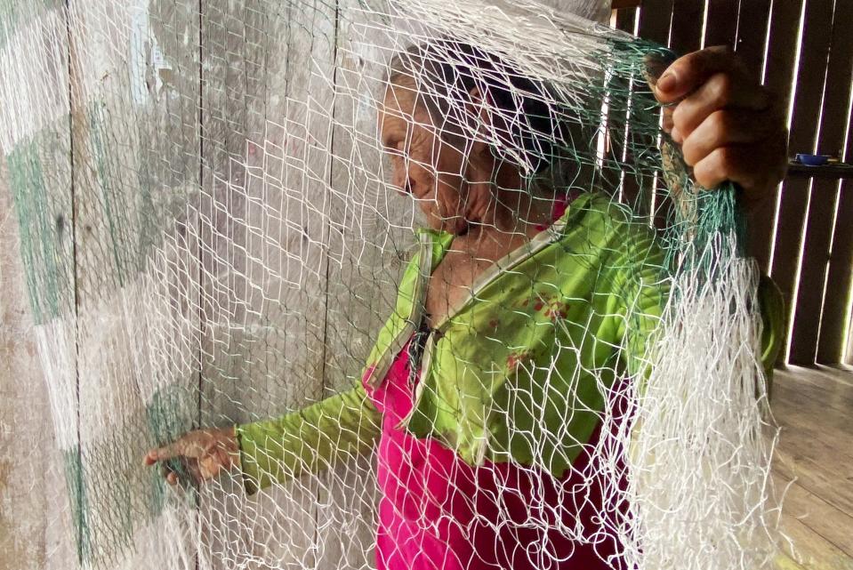 Maria de Fatima da Costa spreads a fishing net in the Sao Gabriel community, Amazonas state, Brazil, March 1, 2023. She is the mother of Amarildo da Costa de Oliveira, who confessed to the killings of Bruno Pereira and Dom Phillips. Pereira was an expert on Indigenous communities and Phillips a British journalist. Da Costa is also the mother of Oseney da Costa de Oliveira, also arrested and accused of the murders. Both are in maximum-security prisons thousands of kilometers away from Javari. (AP Photo/Fabiano Maisonnave)