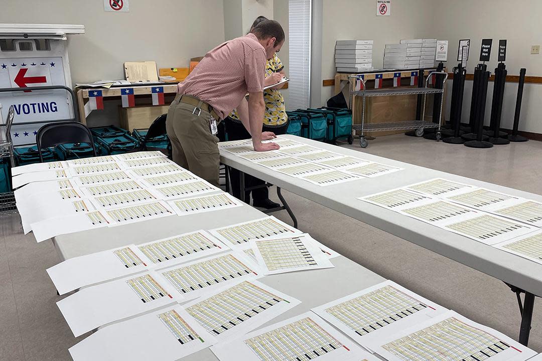 Elections staff surrounded by ballots reviewing precinct totals.