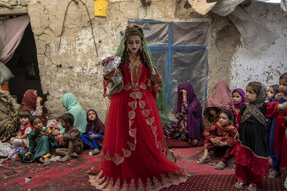 Shamila, 15, from an internally displaced family, adjusts her wedding dress in an old mud house yard, on her wedding day, on the outskirts of Kabul, Afghanistan, Friday, May 19, 2023. “I have no choice. If I don’t accept, my family will be hurt,” she says. Due to poverty and debt, her father had to marry her to a boy at a young age. Her father said that if I did not do this, I might have to give my daughter to someone that I owe. Now, with the money I received from the boy's family, I can pay my debt and treat my son. (AP Photo/Ebrahim Noroozi)